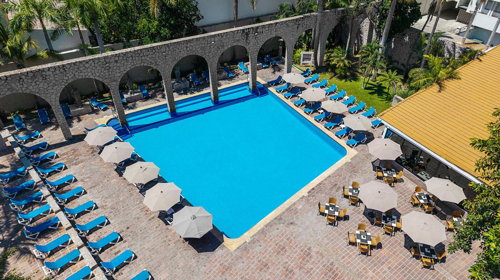 Outdoor pool area with seating and palm trees.