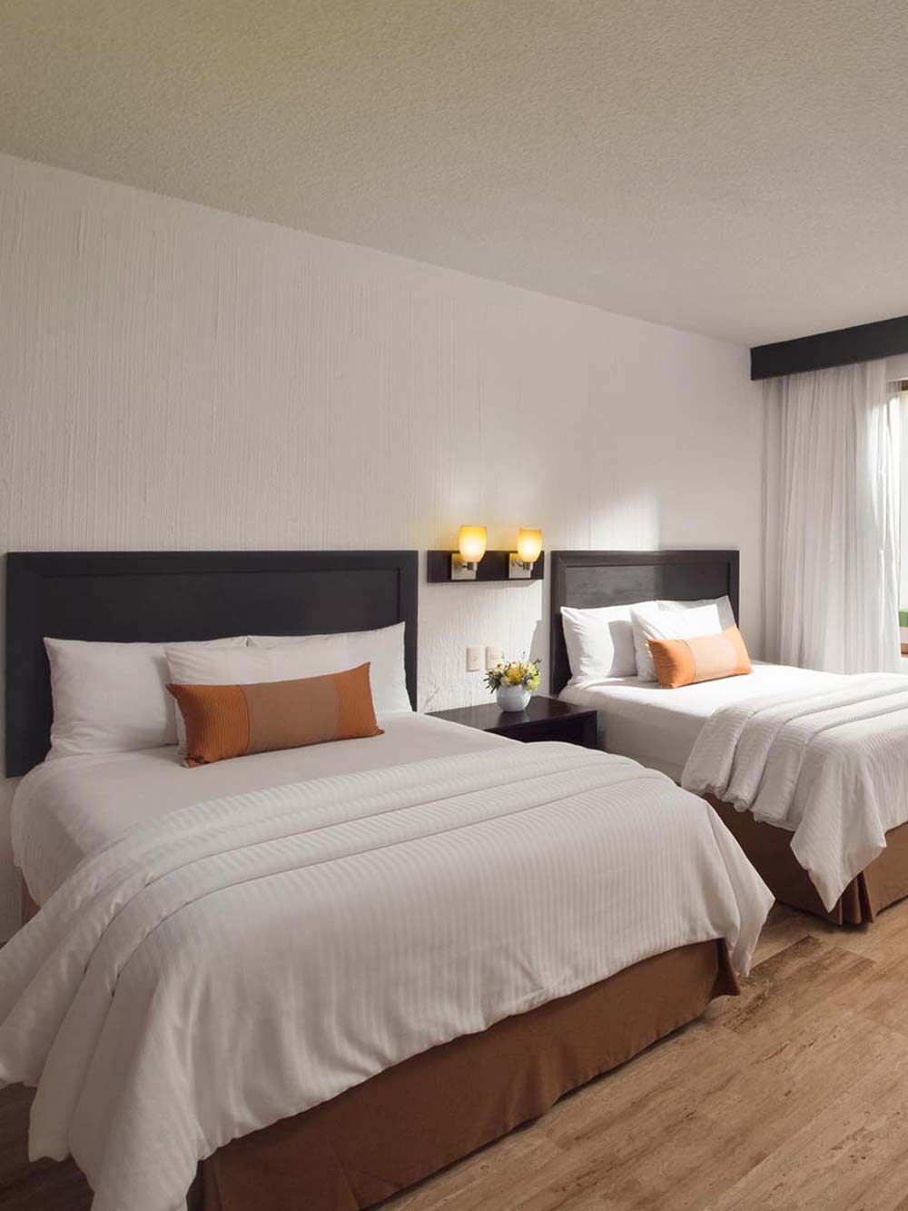 Two king beds with white sheets and pillows in a bright room