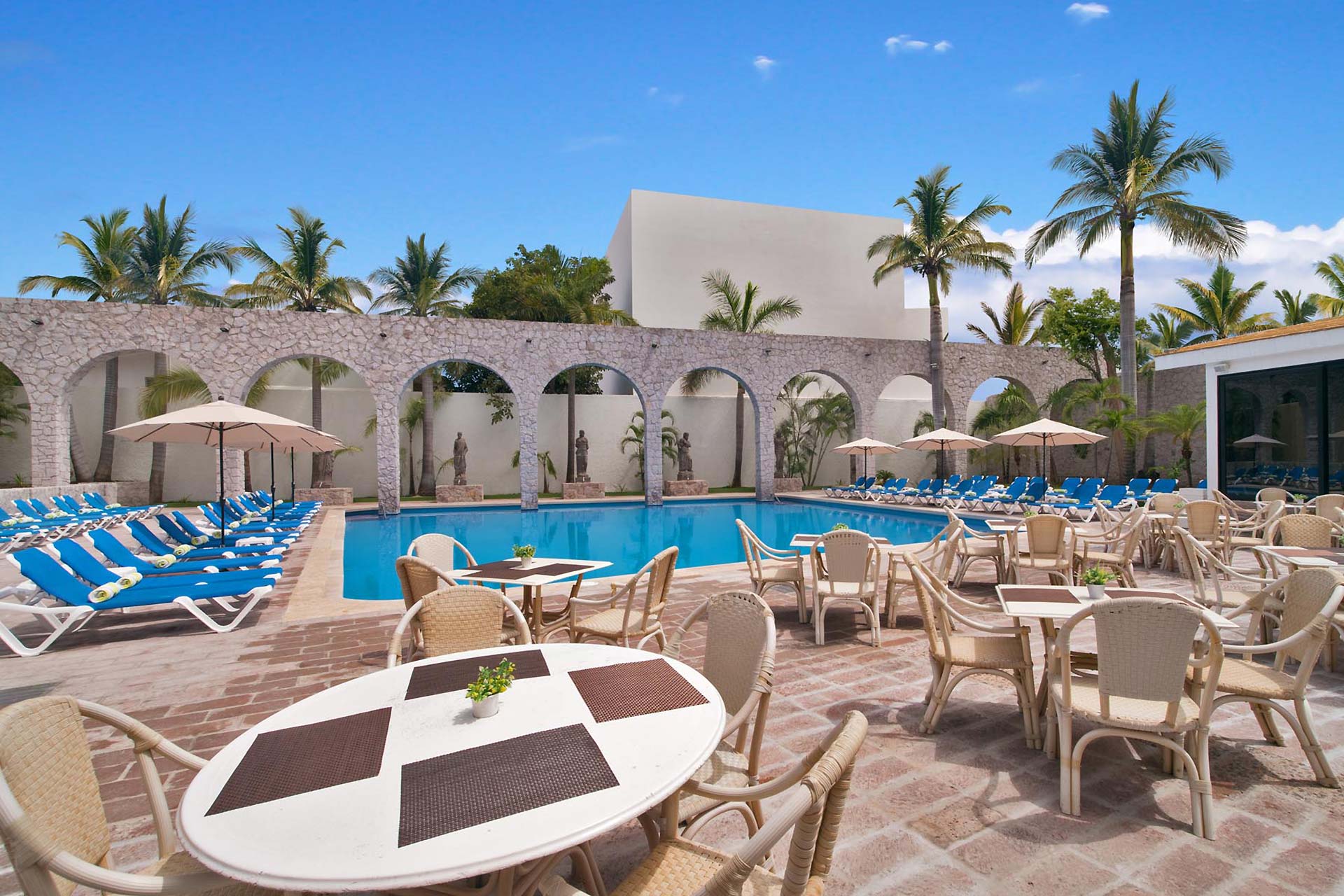 Zona de estar con mesas y sillas junto a la piscina