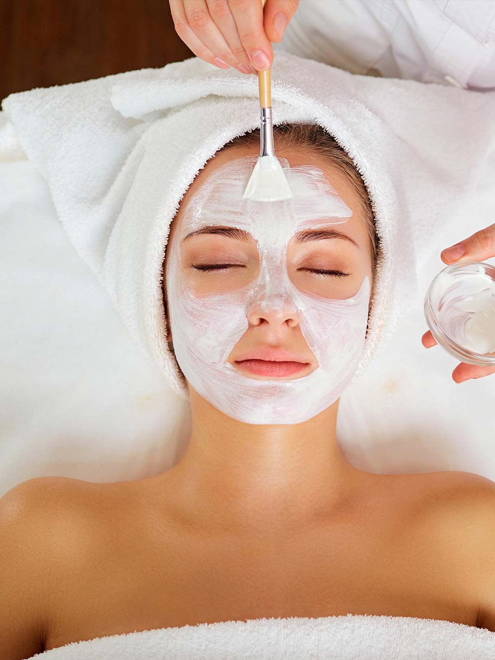 Woman closing her eyes while getting a spa facial treatment